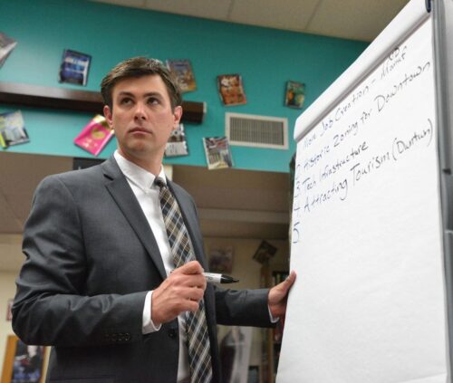 Photo of Drew Awsumb in front of a white board during a presentation.