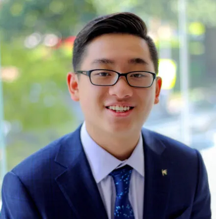Photo of Zishen Ye in blue suit in front of window to outside.