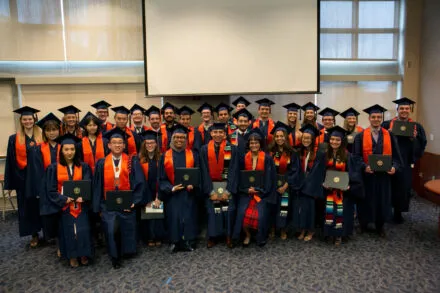 Group photo of graduates in their orange and blue regalia