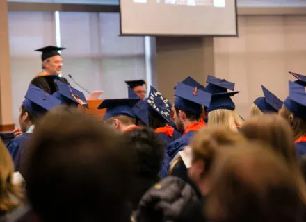 Graduates listening to department head during convocation ceremony