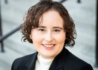 Photo of Emmy Smith in black coat in front of stairs