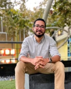 Photo of Omar Perez Figueroa sitting on a bench in an outside courtyard