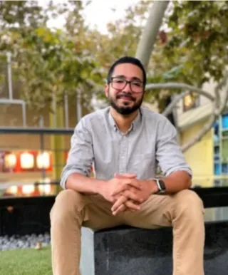 Photo of Omar Perez Figueroa sitting on a bench in an outside courtyard