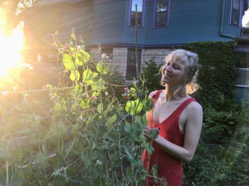 Photo of Rebecca in her garden with the sun shining