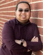 Photo of Luke Talavera in front of a red brick wall