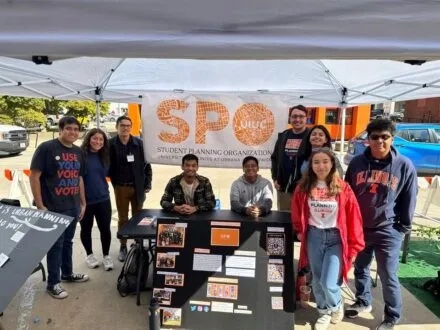 Group photo of SPO members under a tent outside