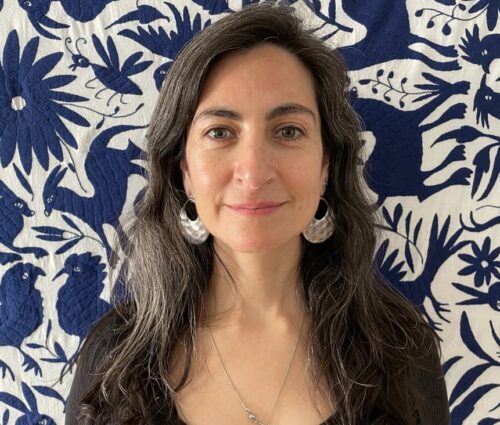 Photo of Daniela in front of a blue and white quilt