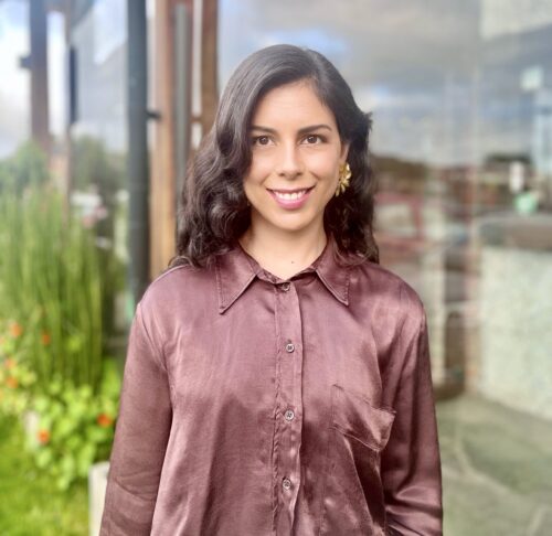 Photo of Camila in rose-colored silk blouse in front of a window