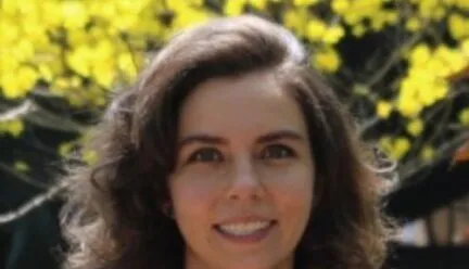 Photo of Julia Paiva in front of a yellow tree
