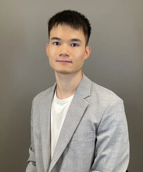 Photo of Rongxiang Su in grey suit against brownish background