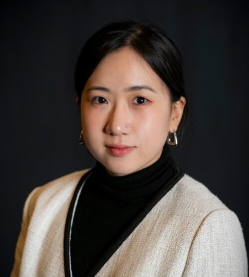 Photo of Nadia Kim in white blazer with a black background
