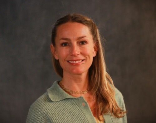 Photo of Amanda Merck in a green sweater against a dark backdrop