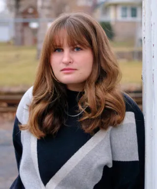 Photo of Emily Guske in a black and gray sweater outside