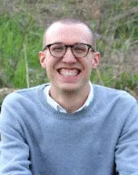 Photo of JD McClanahan sitting outside in a blue sweater