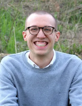 Photo of JD McClanahan sitting outside in a blue sweater