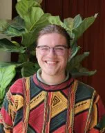 Photo of Brandon Snyder in colorful sweater in front of a green plant and orange curtain