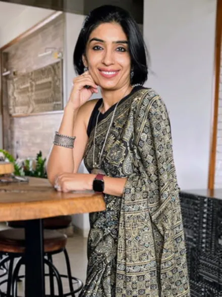 Photo of Mansi Sachdev standing at a table with a white background