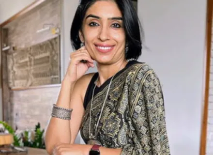 Photo of Mansi Sachdev standing at a table with a white background