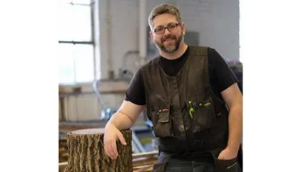 Lowell Miller with a tree stump in the fabrication shop