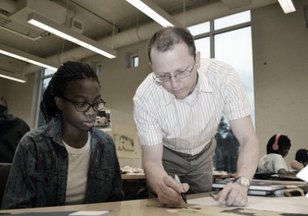 Professor and students looking over work in studio