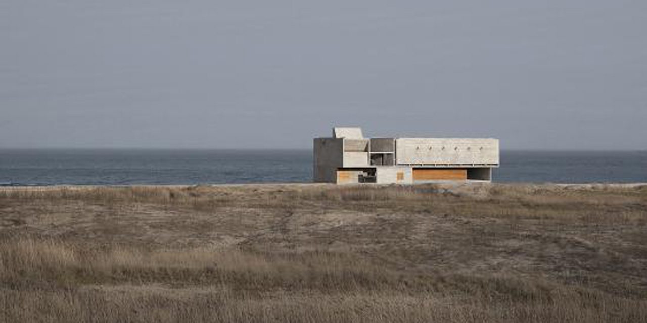 View of building along horizon with field in foreground 