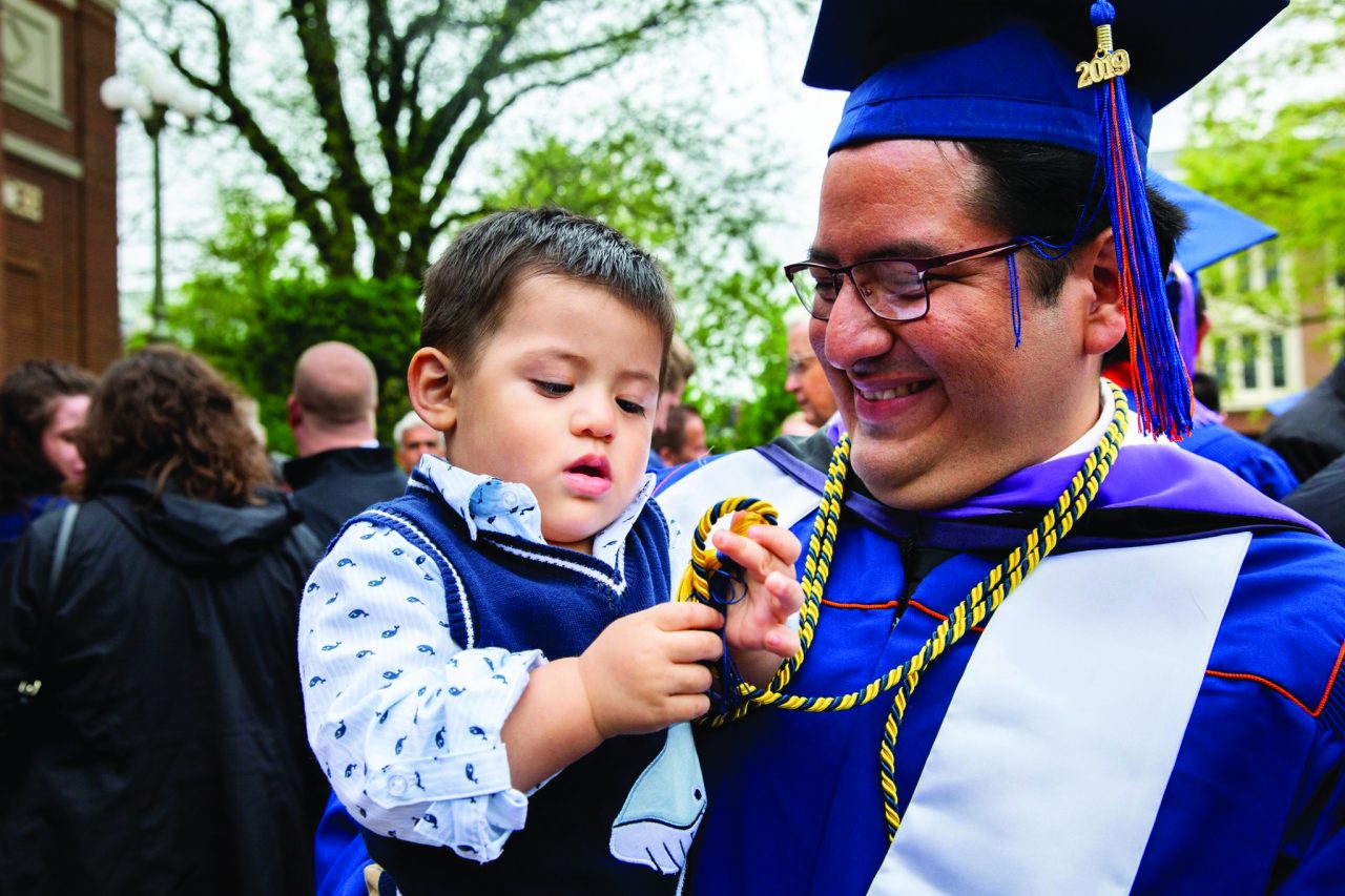 Adult in graduation garb holding young boy