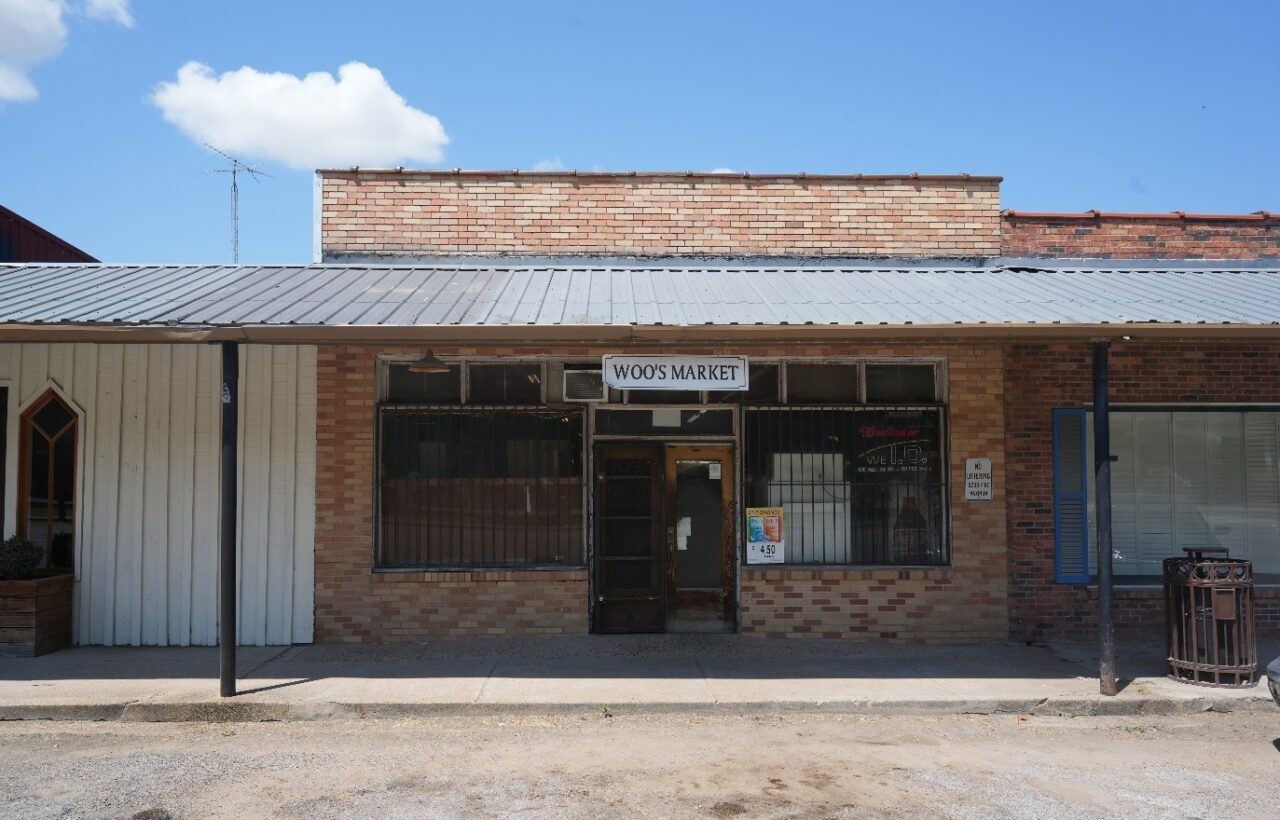 an old fashioned brick market with awning called "woo's market"