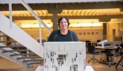 carol ross barney standing in front of an architect model in her work space.