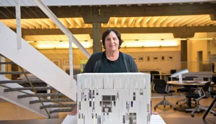 carol ross barney standing in front of an architect model in her work space.