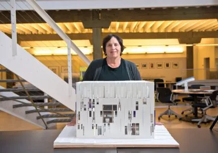 woman standing in atrium smiling at camera behind an architectural model