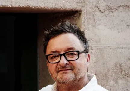 man looking at camera intently, white shirt, black rimmed glasses, spiked hair