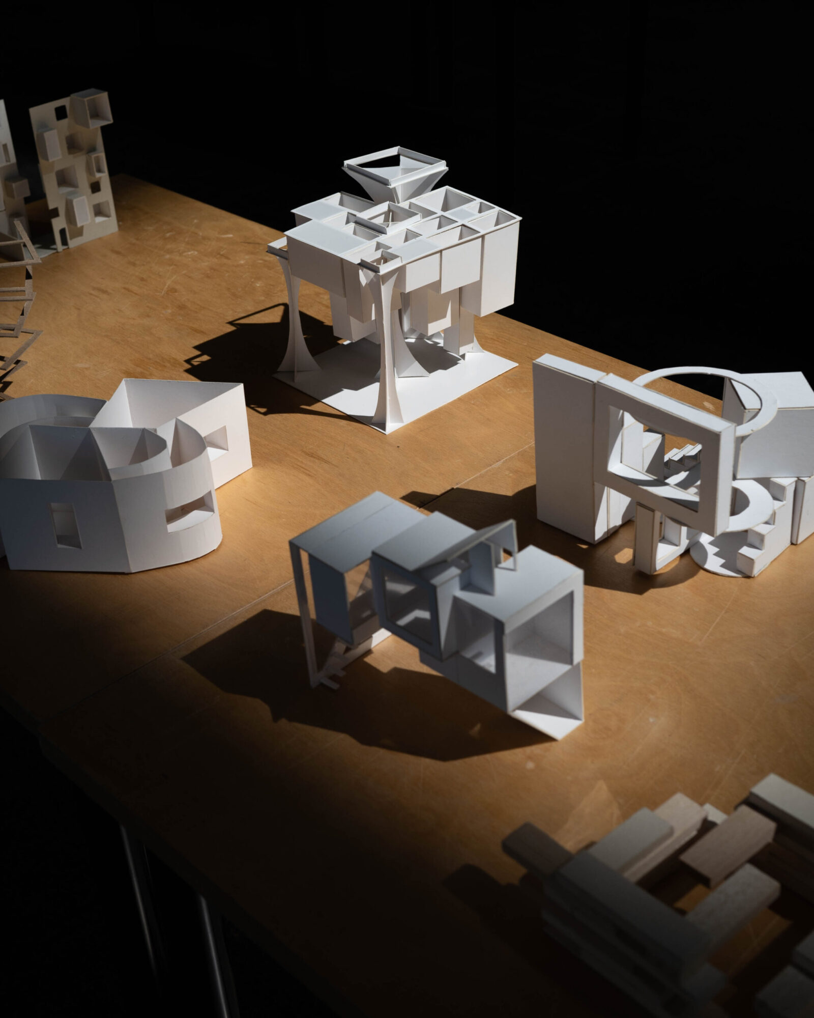 a shadowed picture of multiple student projects, all created out of white cardboard or paper