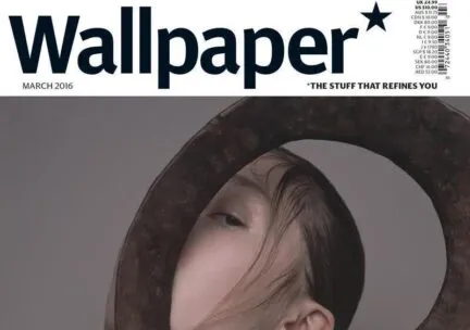 wallpaper magazine cover with a woman half face hiding behind round bottlecap made out of stone with gold necklace