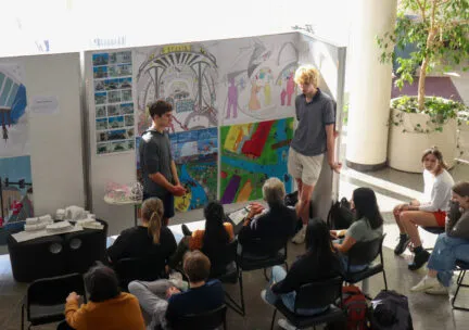 students presenting in the atrium in front of a z panel