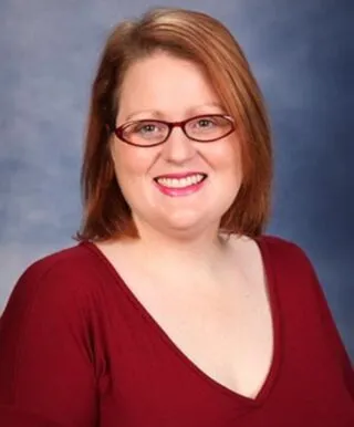 kristie stramaski, red hair, blouse, red glasses, smiling at camera