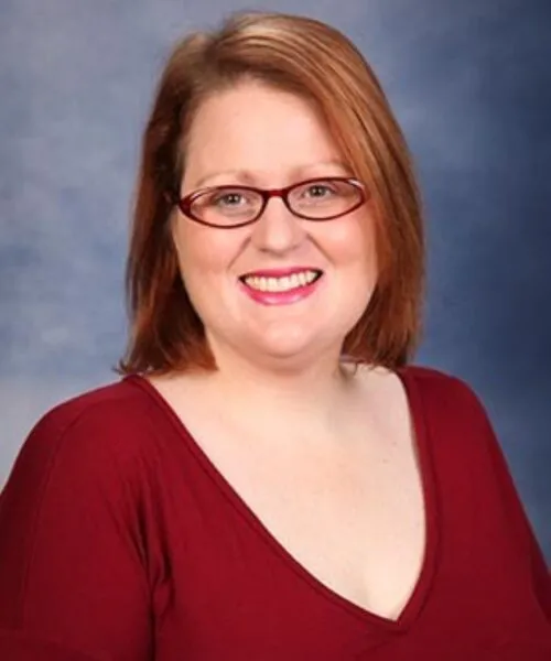 kristie stramaski, red hair, blouse, red glasses, smiling at camera