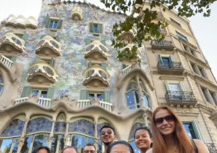 students smiling at camera in front of beautiful building