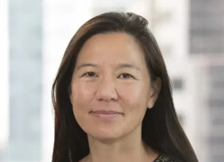 olive complexion with long black hair, smiling mouth closed at camera, wearing patterned top