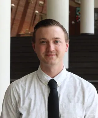white male short hair white shirt black tie closed mouth smile looking at camera
