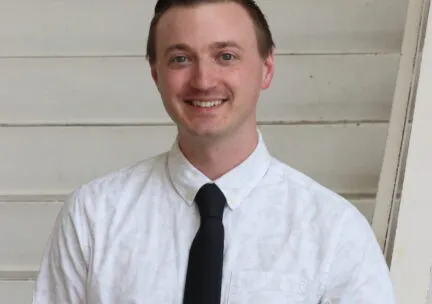 man smiling at camera white shirt black tie