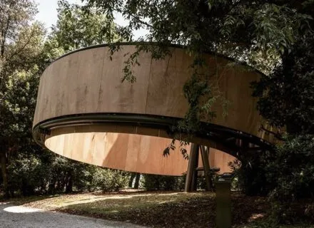 circular wooden building angled off the ground without a roof 