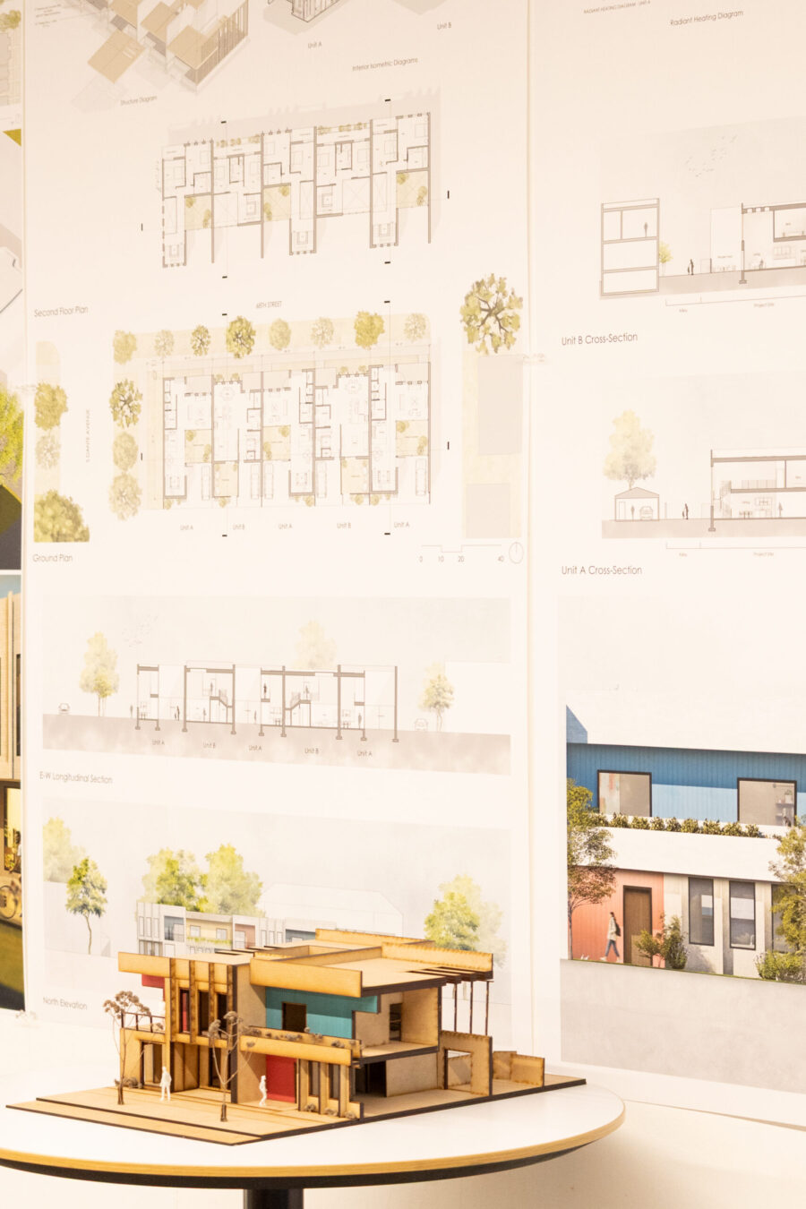 a model of a building with blueprints pinned up behind it