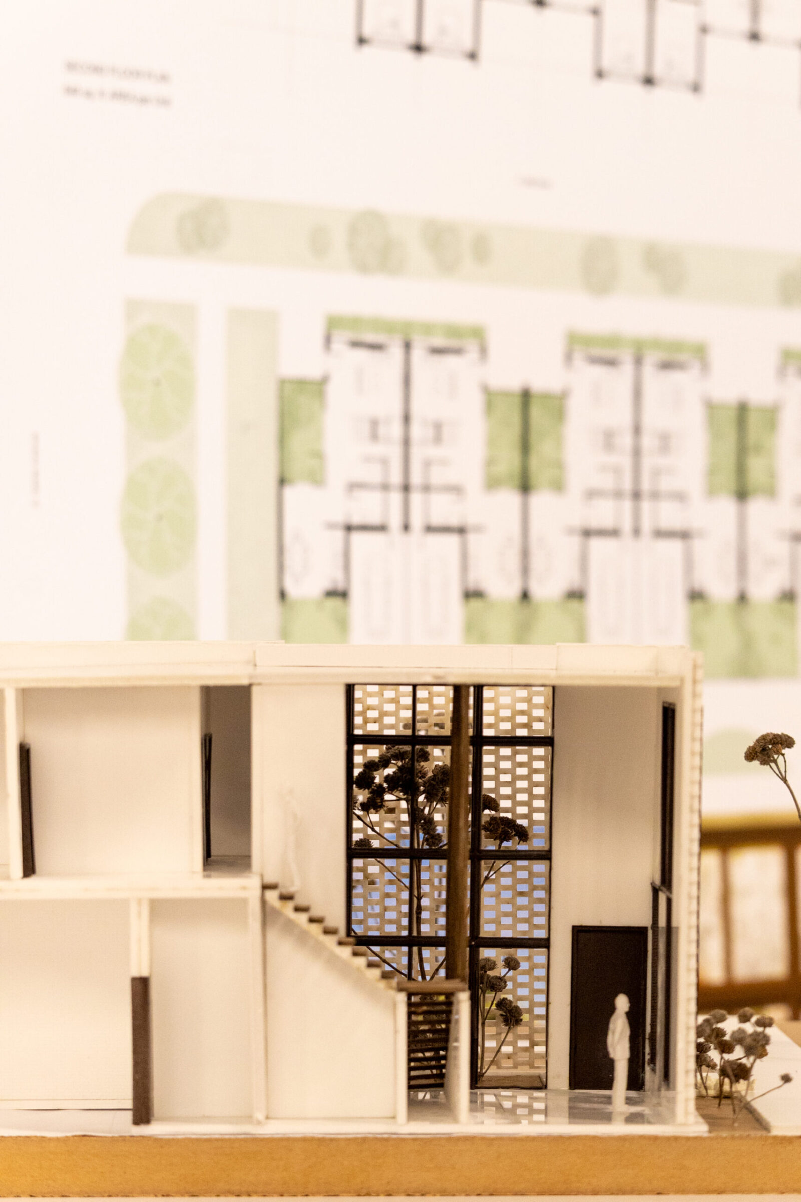 a building model with blueprints pinned up behind it