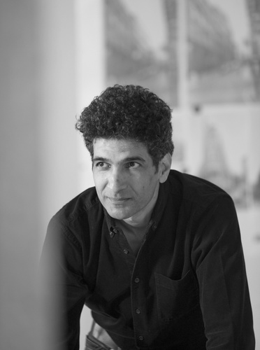 man in orange shirt black skin arms crossed looking focused at the camera