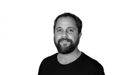 man in black tshirt in black and white photo smiling at camera beard and short hair