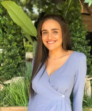 tan complexion woman smiling into camera with blue skirt hip length black hair