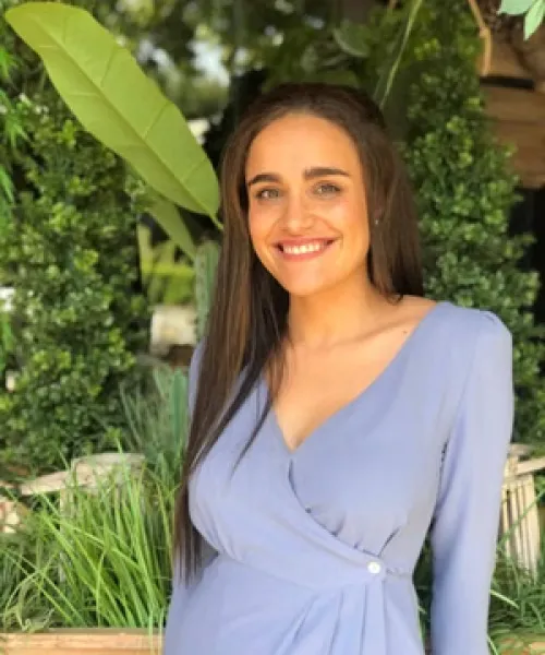 tan complexion woman smiling into camera with blue skirt hip length black hair