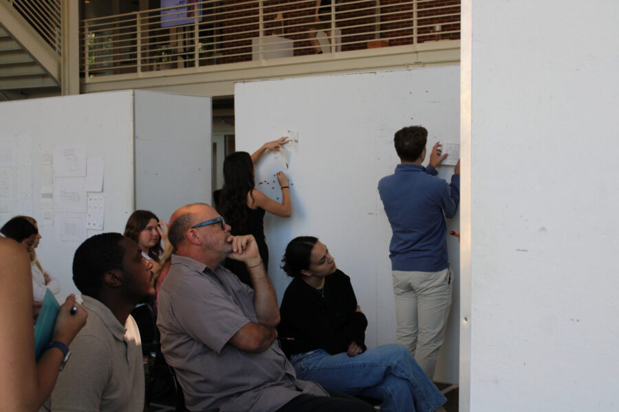 students pinning up projects behind an audience