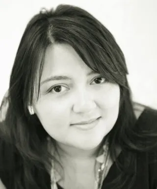 woman smiling into camera, chest length black hair framing the face, black and white photo