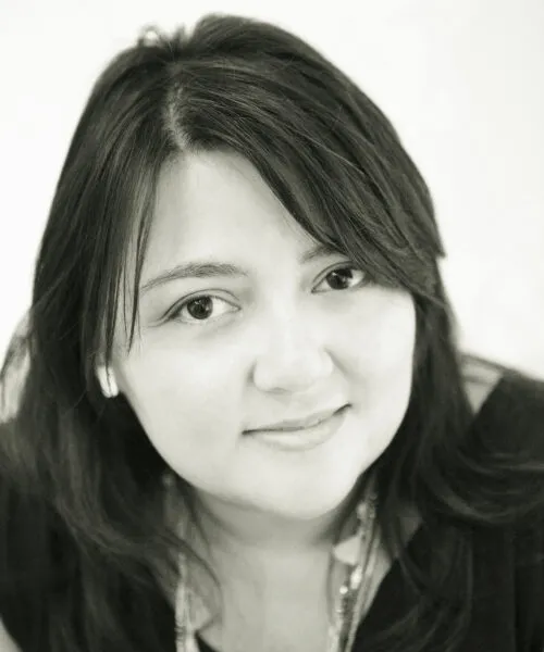 woman smiling into camera, chest length black hair framing the face, black and white photo
